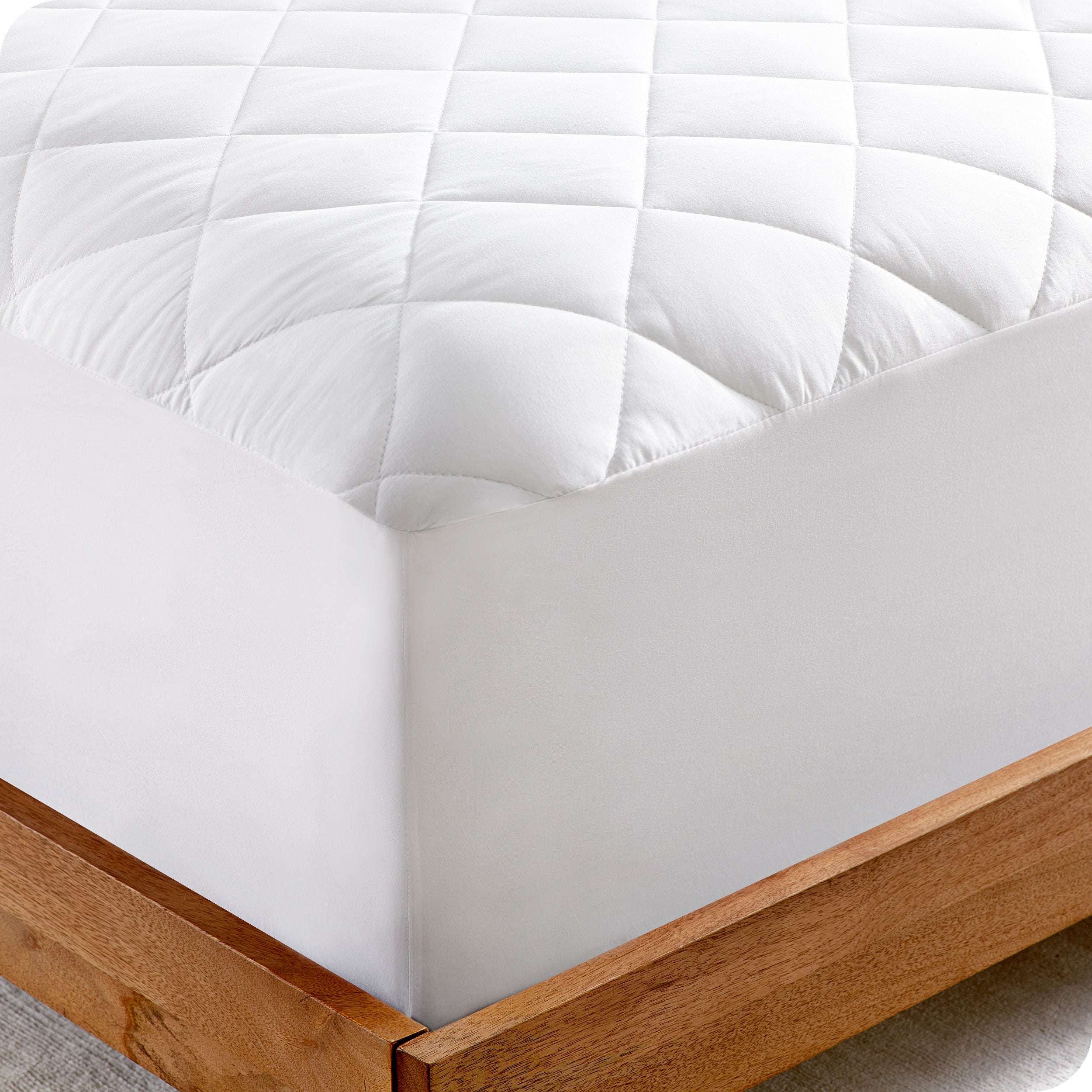 The corner of a bed showing the texture of the quilted mattress pad.
