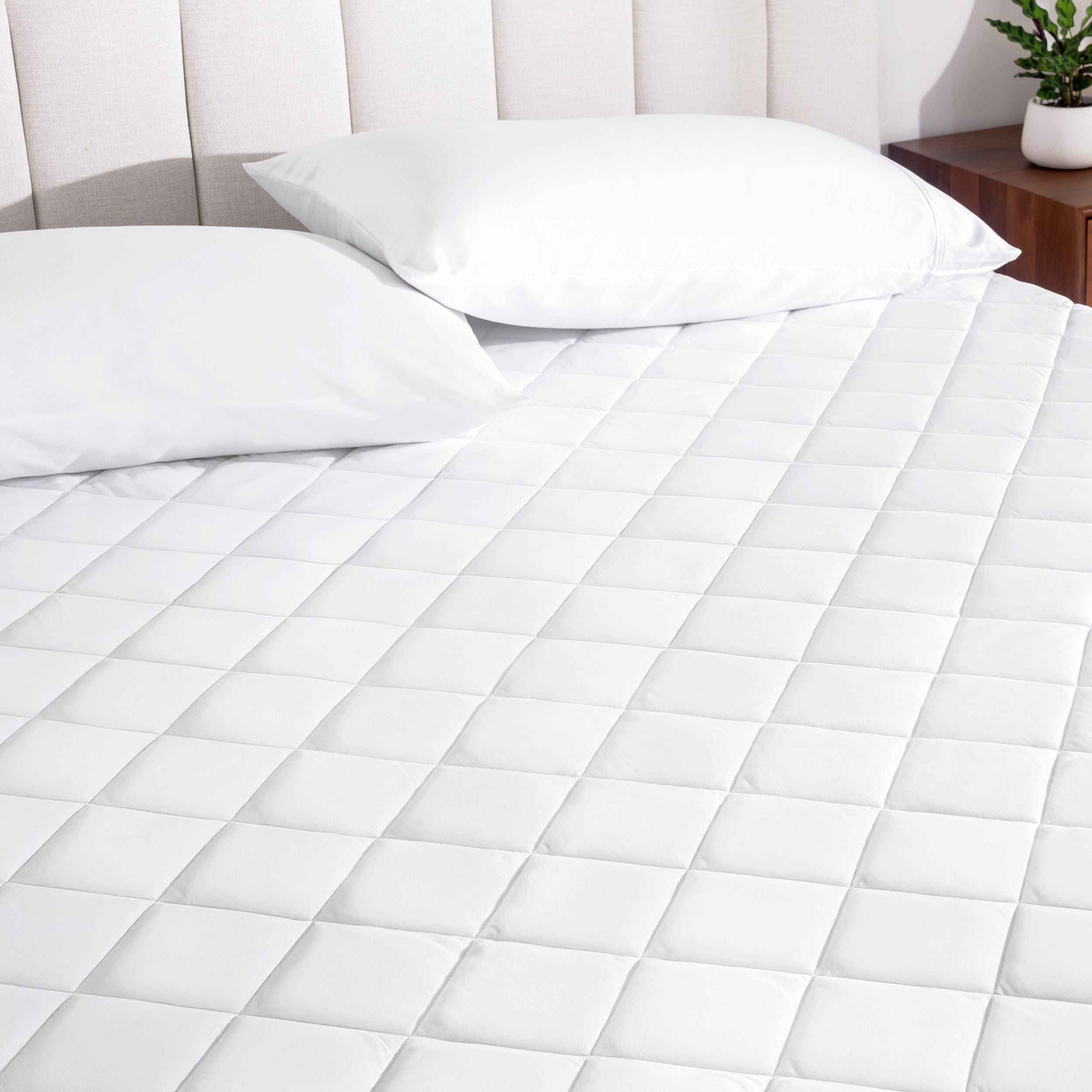 A mattress pad on a bed with two pillows from above.