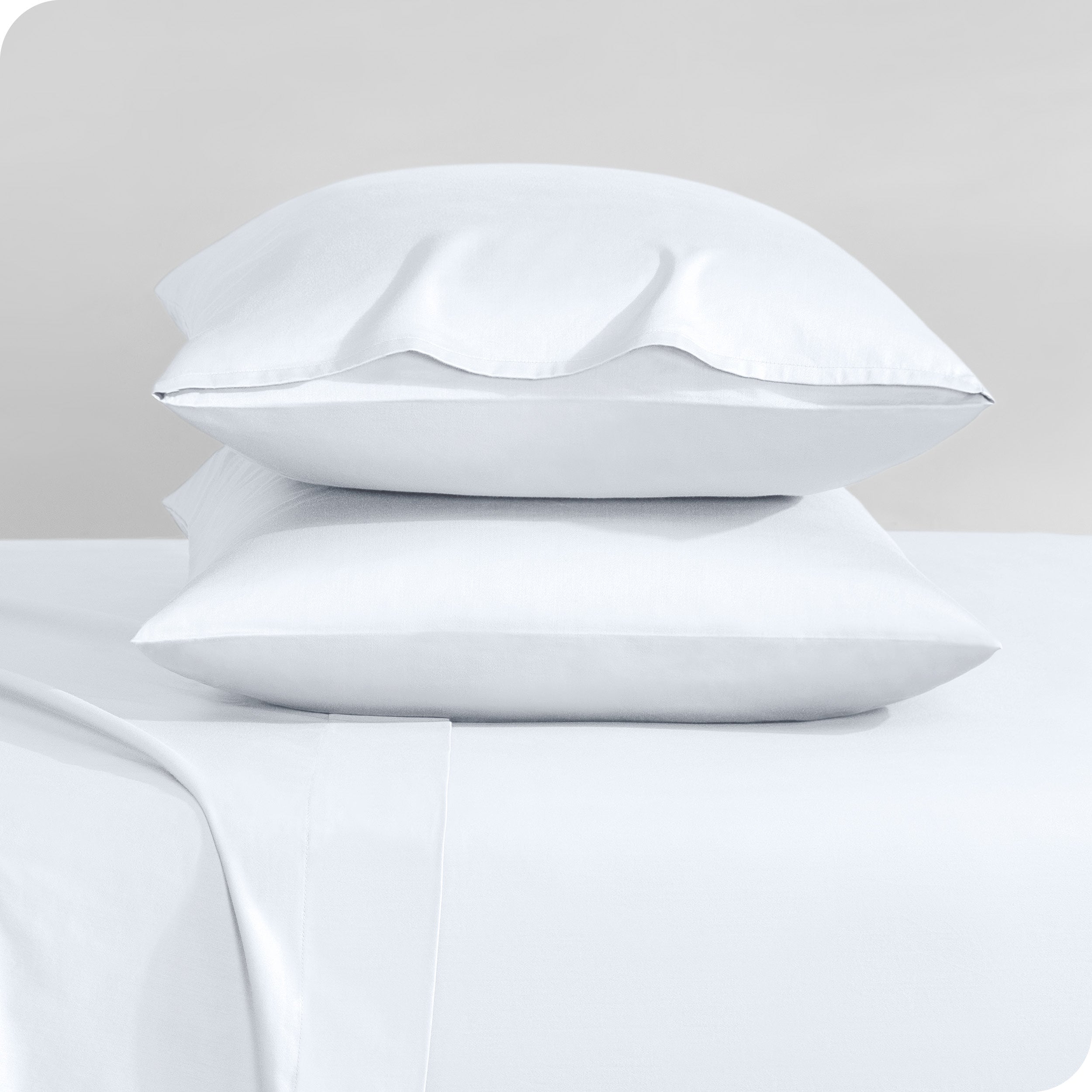 Two sateen pillowcases stacked on a bed