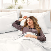 A woman sleeping on a bed made with organic cotton sateen sheets and pillowcases
