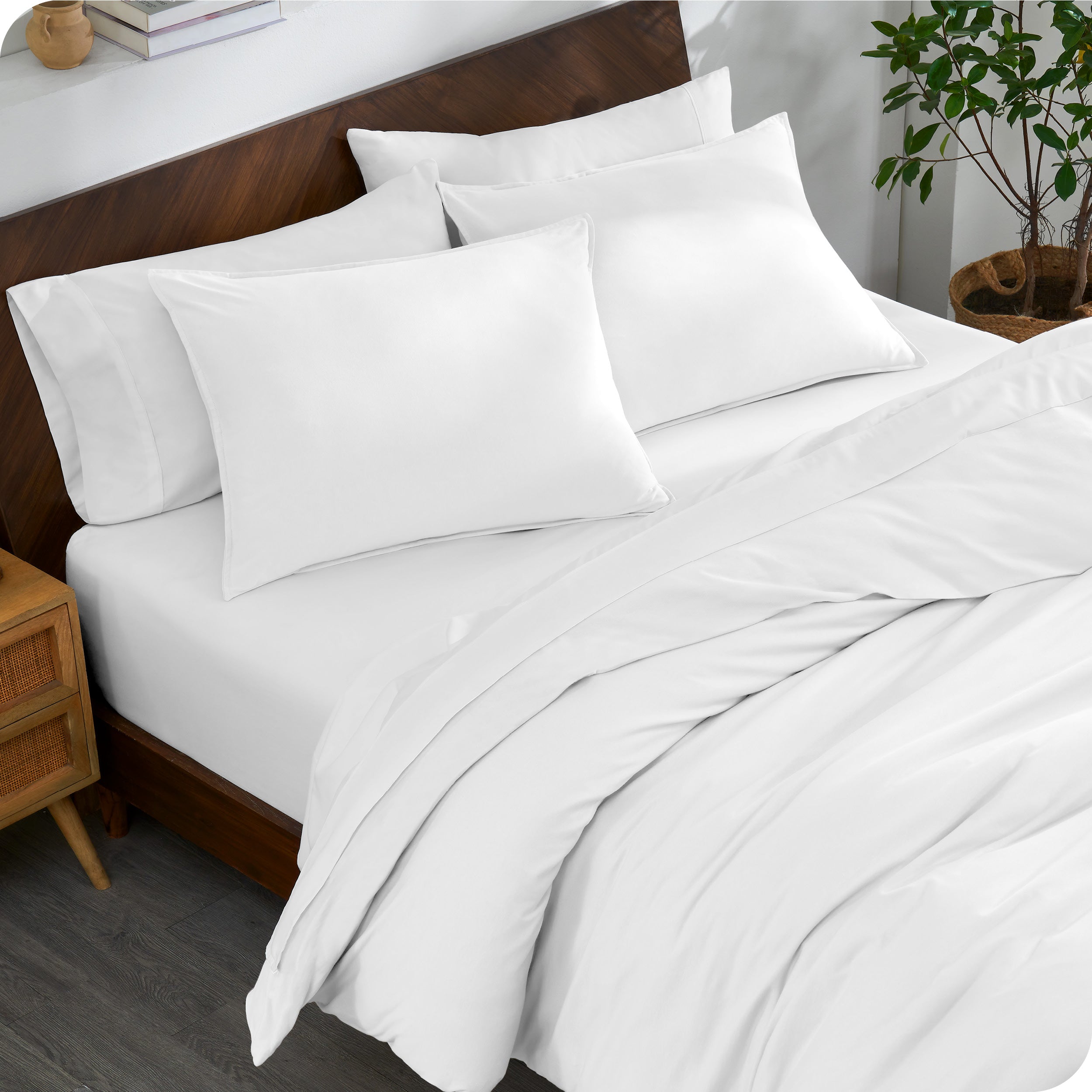 A bed made with an organic jersey duvet cover, pillow sham covered pillows and extra pillows