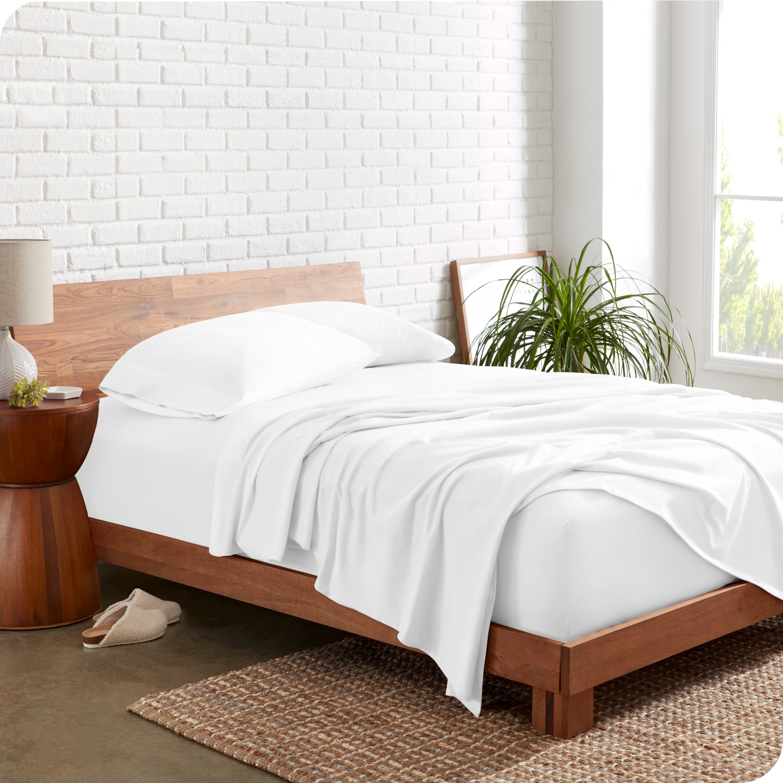 Organic jersey sheets on a bed with a brick wall behind the headboard
