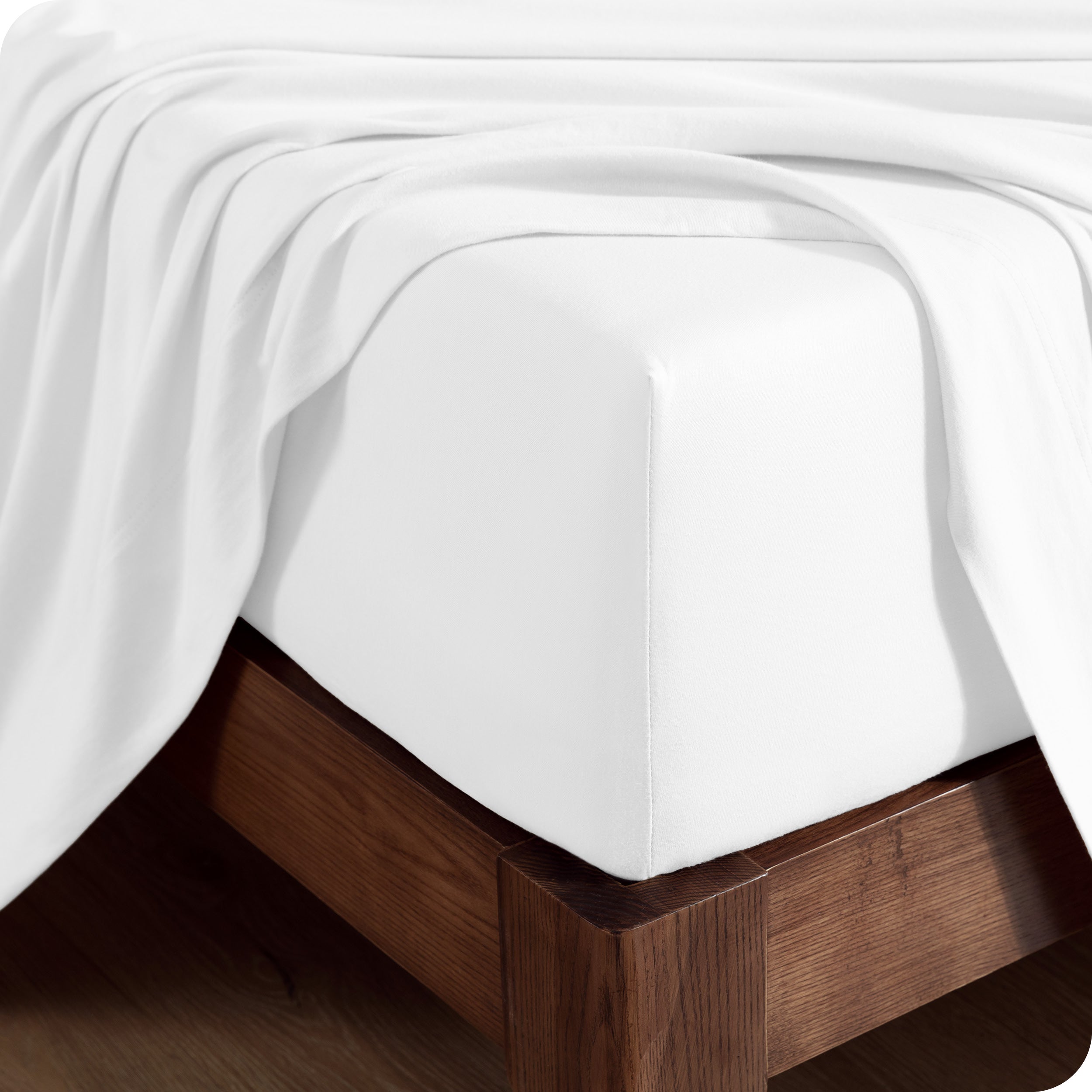 Close up of the corner of a mattress with a fitted sheet and flat sheet on it