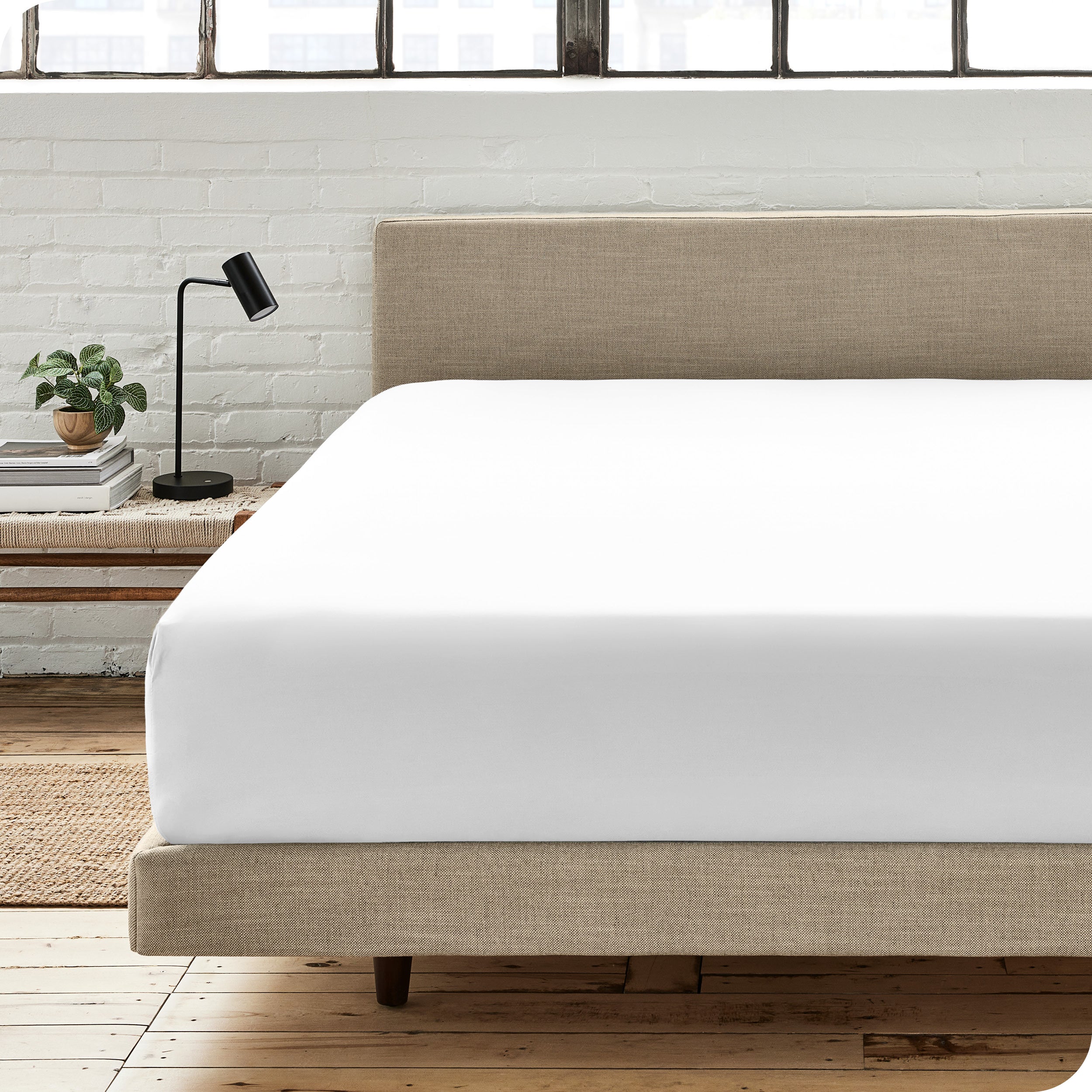 A percale fitted sheet on a bed with table next to it
