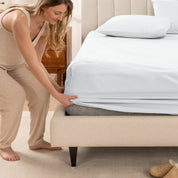 A women is putting on the percale fitted sheet on the bed