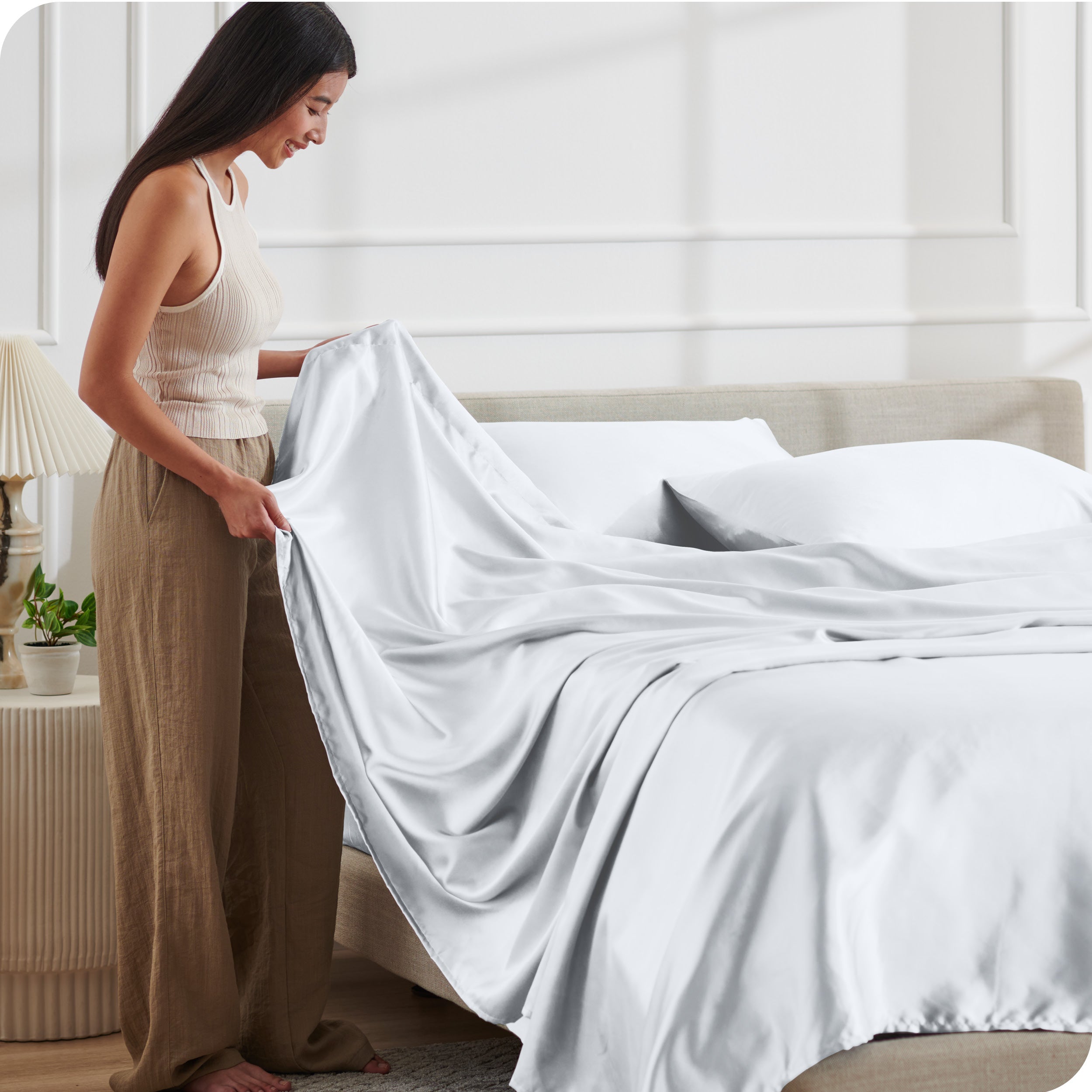 A woman making a bed with satin sheets