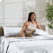 A woman sitting on a bed made with satin sheets
