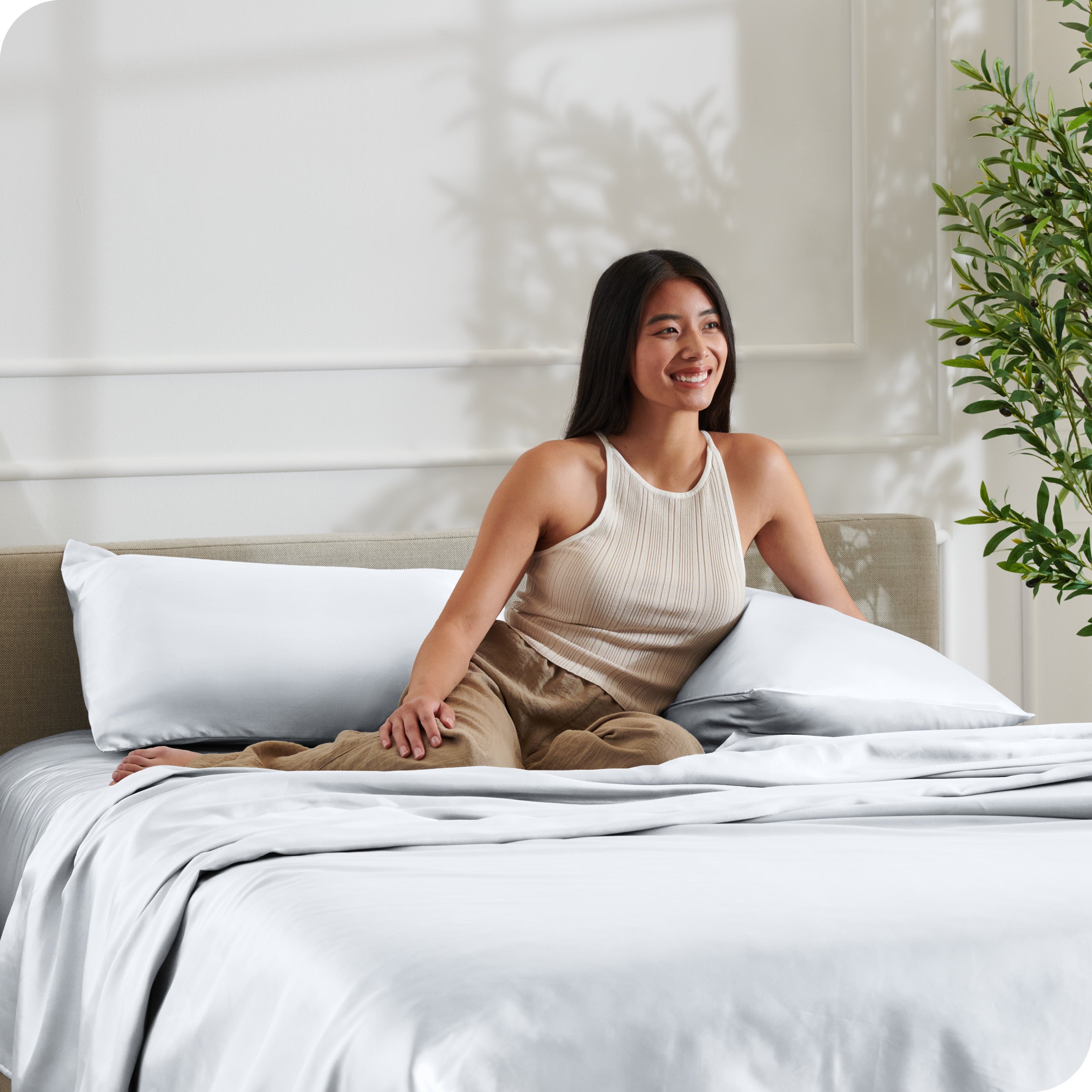 A woman sitting on a bed made with satin sheets