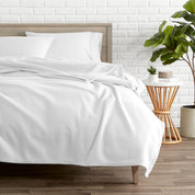 A polar fleece blanket on a bed next to a table and a large plant