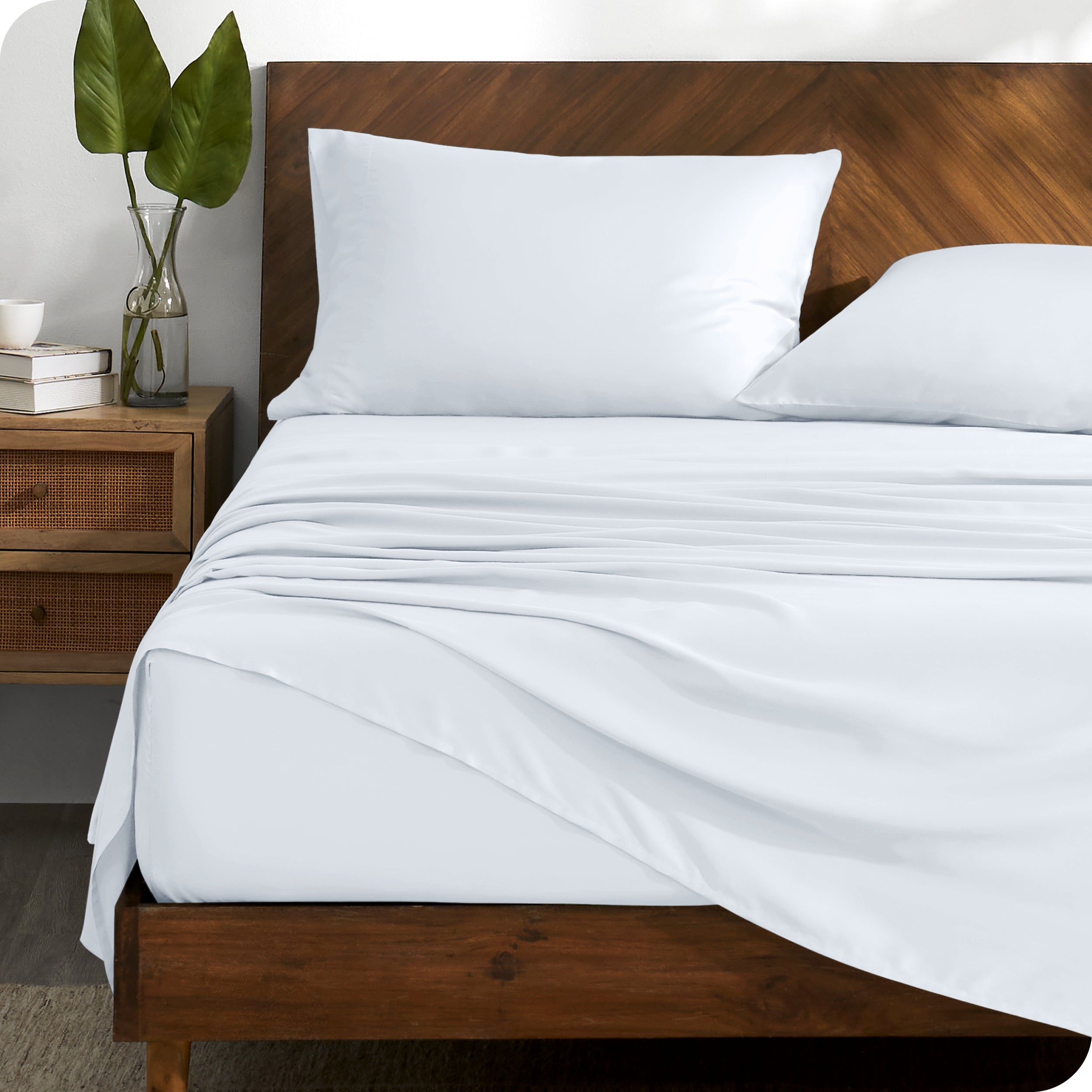 TENCEL™ sheet set on a bed with the flat sheet loosely draped over the top. The mattress is on a wooden bed frame.