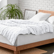 A cotton weighted blanket is loosely draped over a bed