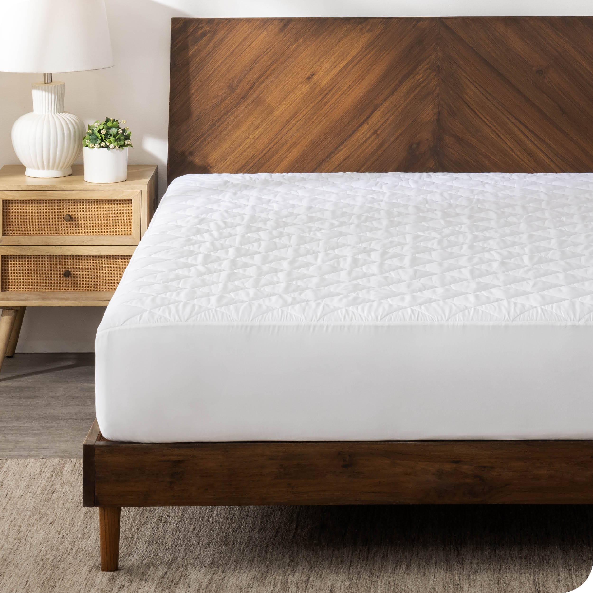 A modern bedroom with a white mattress pad on the bed.