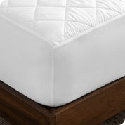 Close up of the corner of a mattress with a mattress pad on it