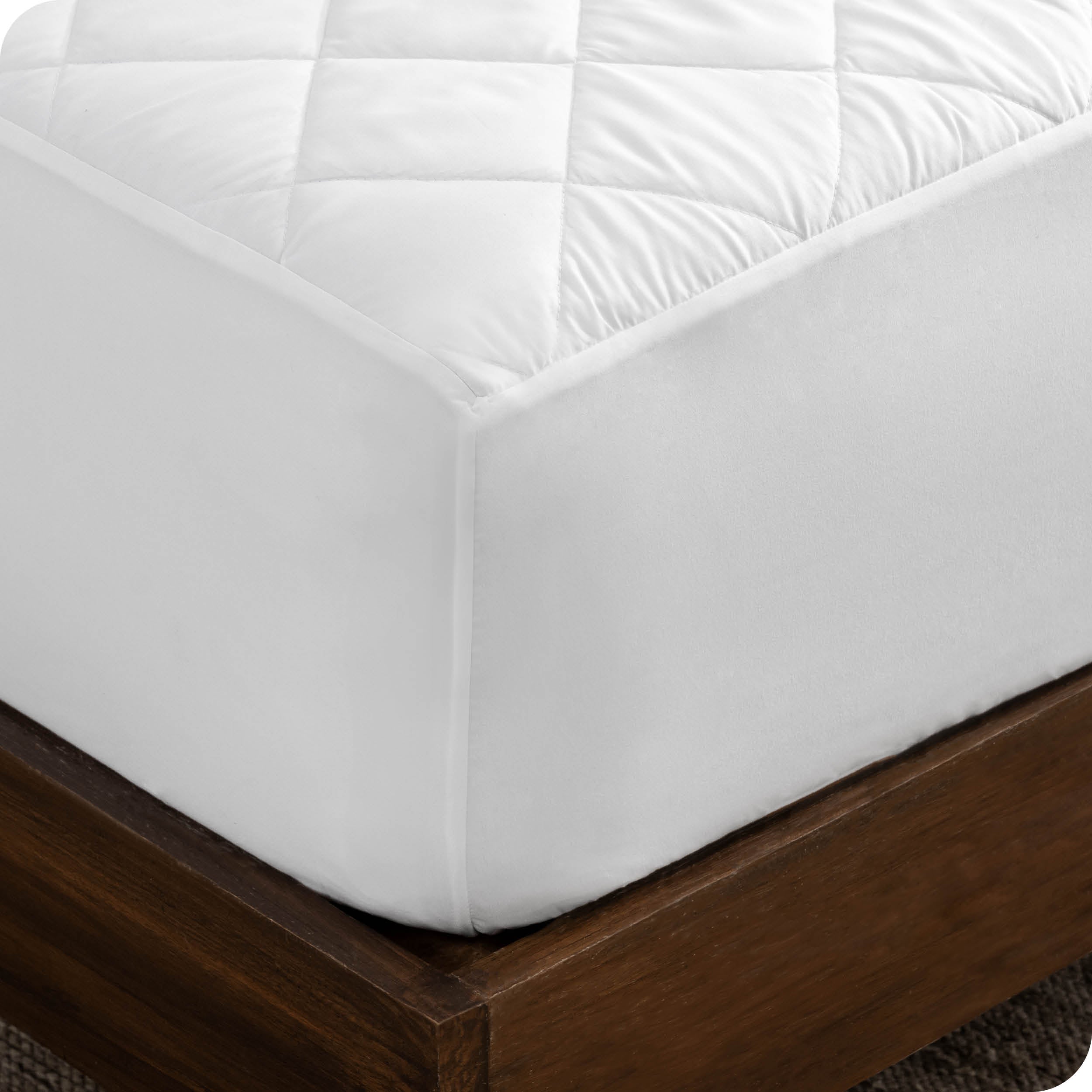 Close up of the corner of a mattress with a mattress pad on it