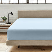A percale fitted sheet on a bed with table next to it