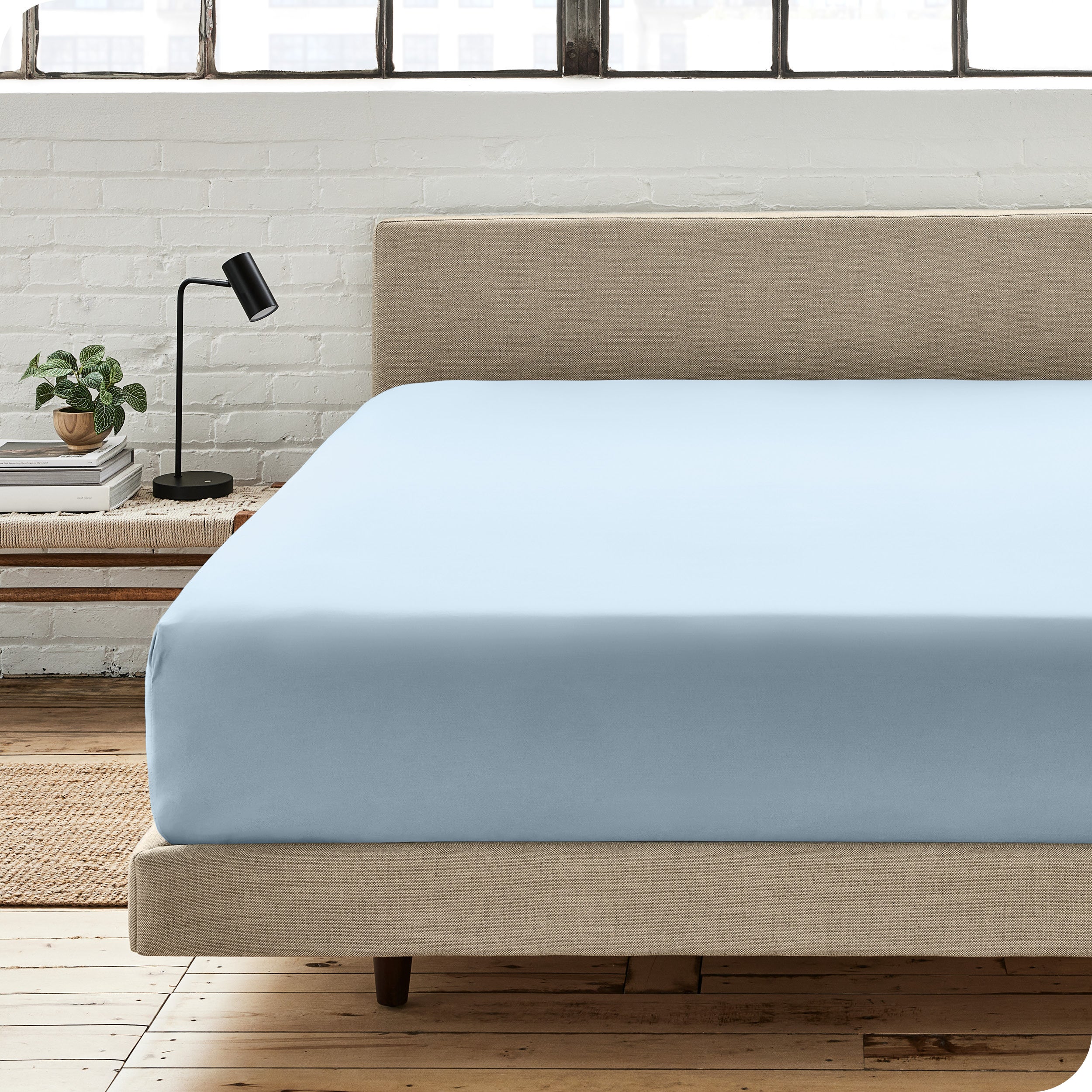 A percale fitted sheet on a bed with table next to it