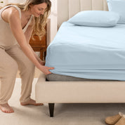 A women is putting on the percale fitted sheet on the bed