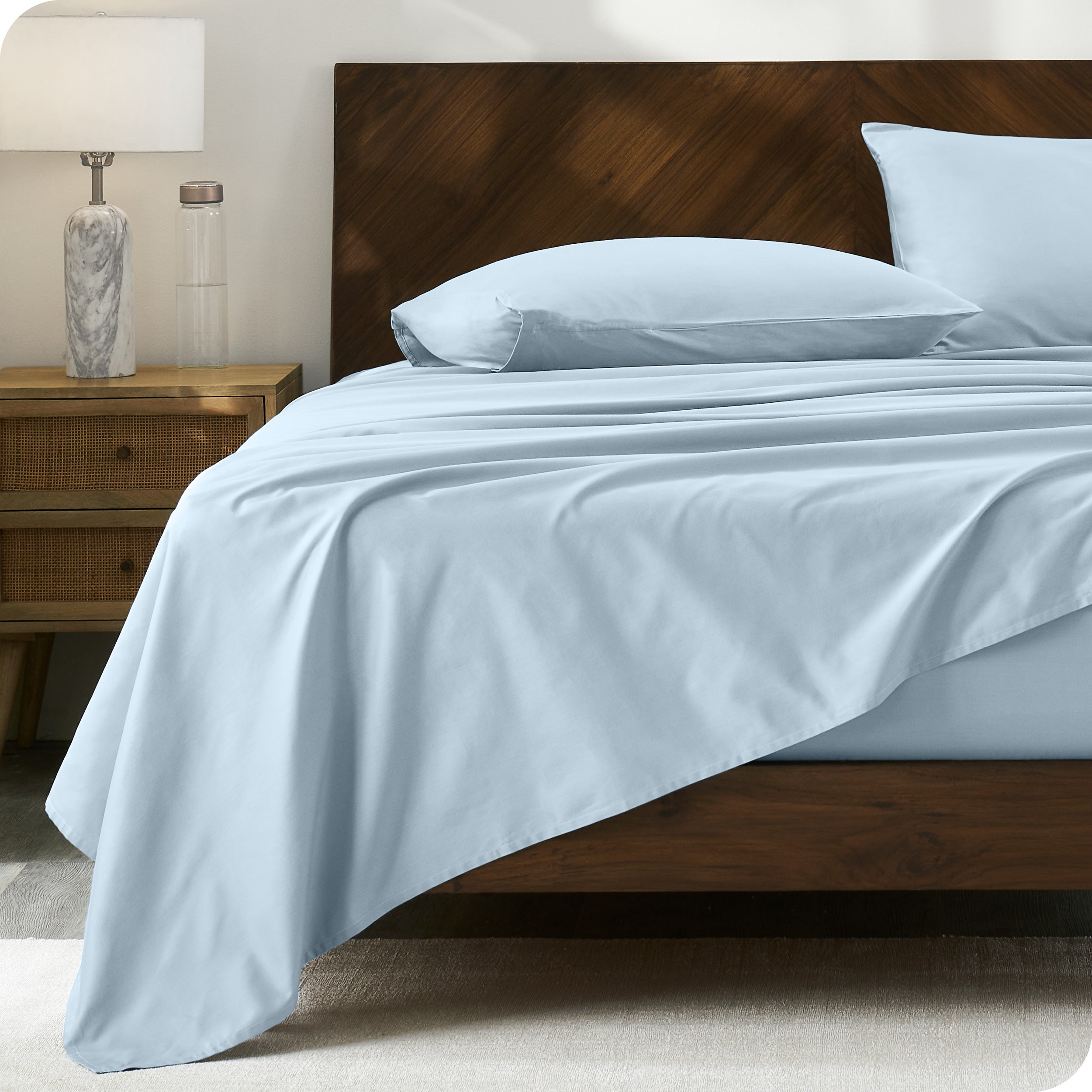 Percale sheet set on a bed with a wooden headboard