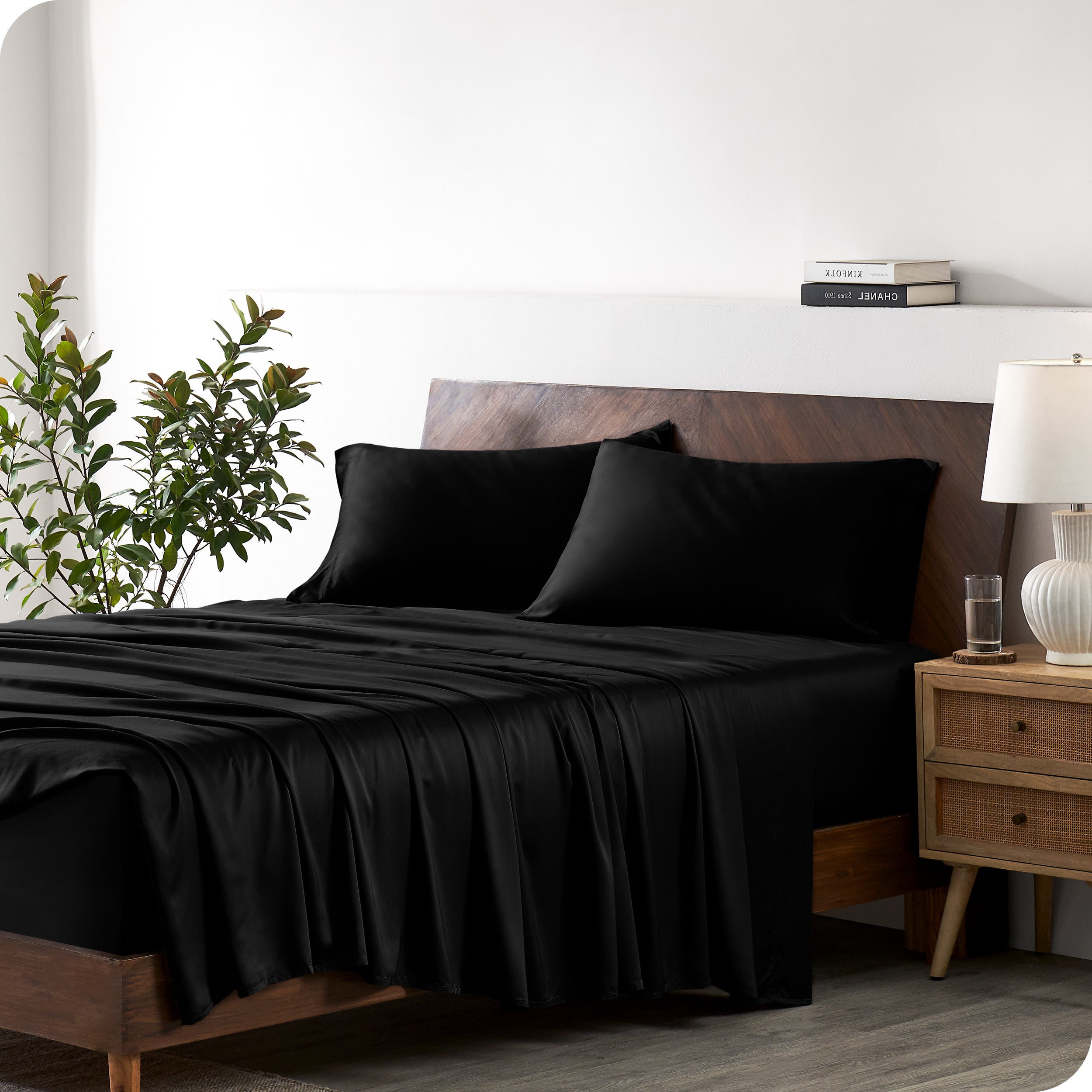 Modern bedroom with a bed against a white wall with a nightstand next to the bed. The bed has bamboo sheets draped over it.