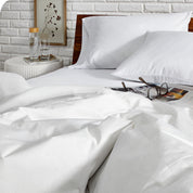 Close up of a down comforter on a bed with a magazine and glasses on it