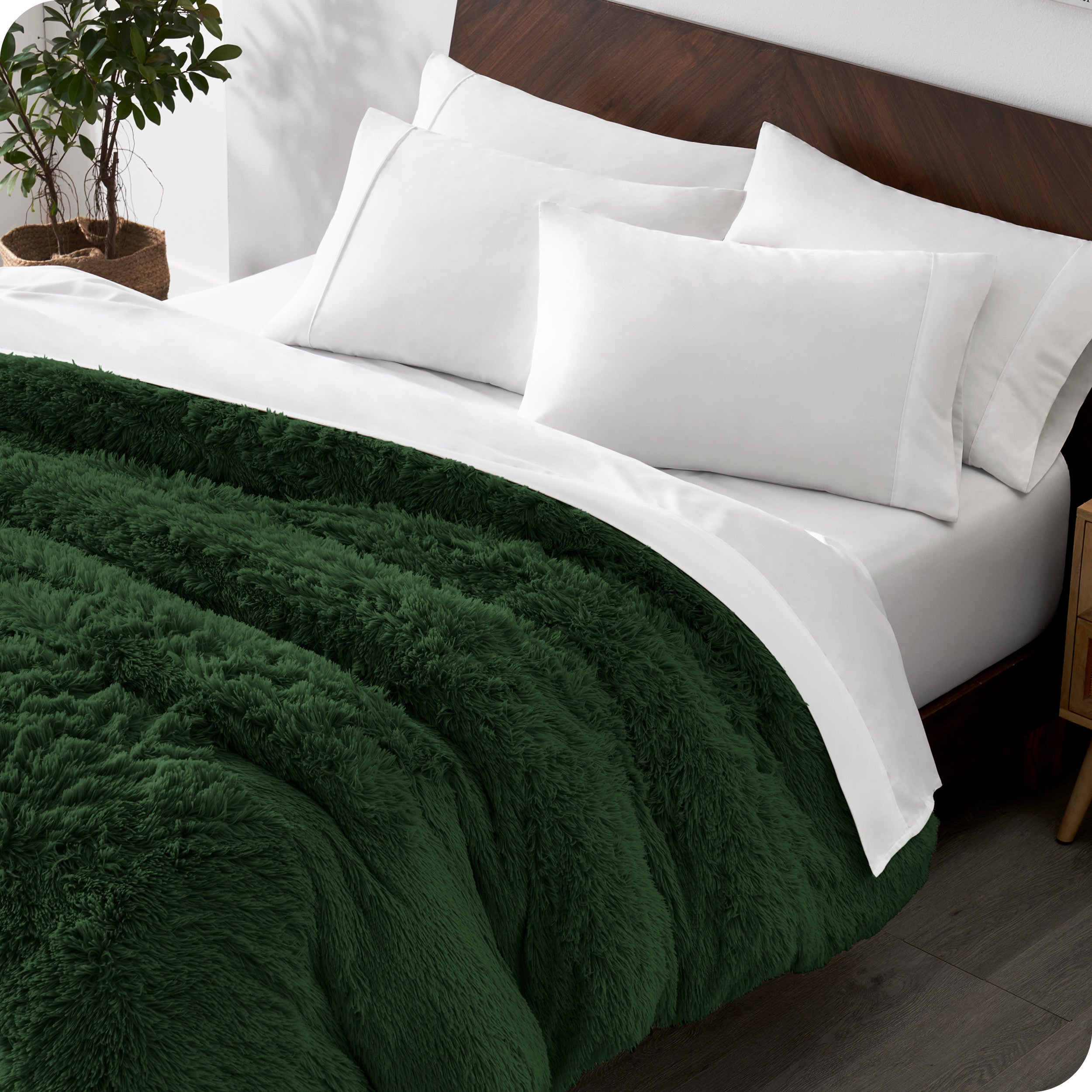 Diagonal view of a bed made with white sheets and pillowcases with a green shaggy duvet cover on top