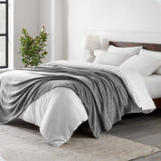 A sideview of a modern bed with a wooden bedframe and our polar fleece blanket on top of the bed.
