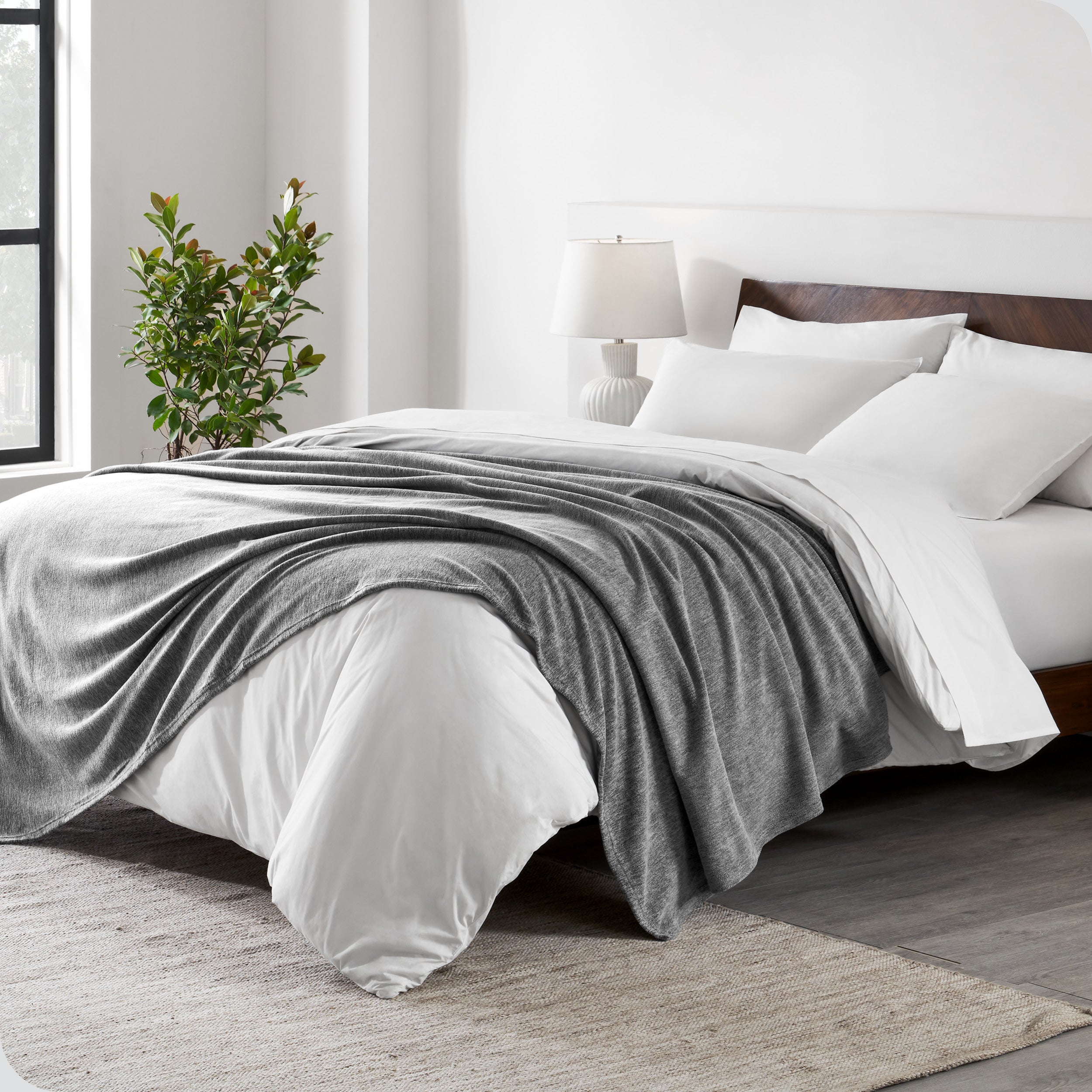 A sideview of a modern bed with a wooden bedframe and our polar fleece blanket on top of the bed.