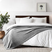 A sideview of a modern bed with a wooden bedframe and our polar fleece blanket on top of the bed.