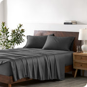 Modern bedroom with a bed against a white wall with a nightstand next to the bed. The bed has bamboo sheets draped over it.