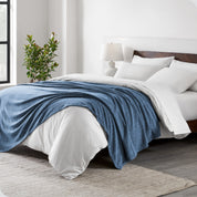 A sideview of a modern bed with a wooden bedframe and our polar fleece blanket on top of the bed.