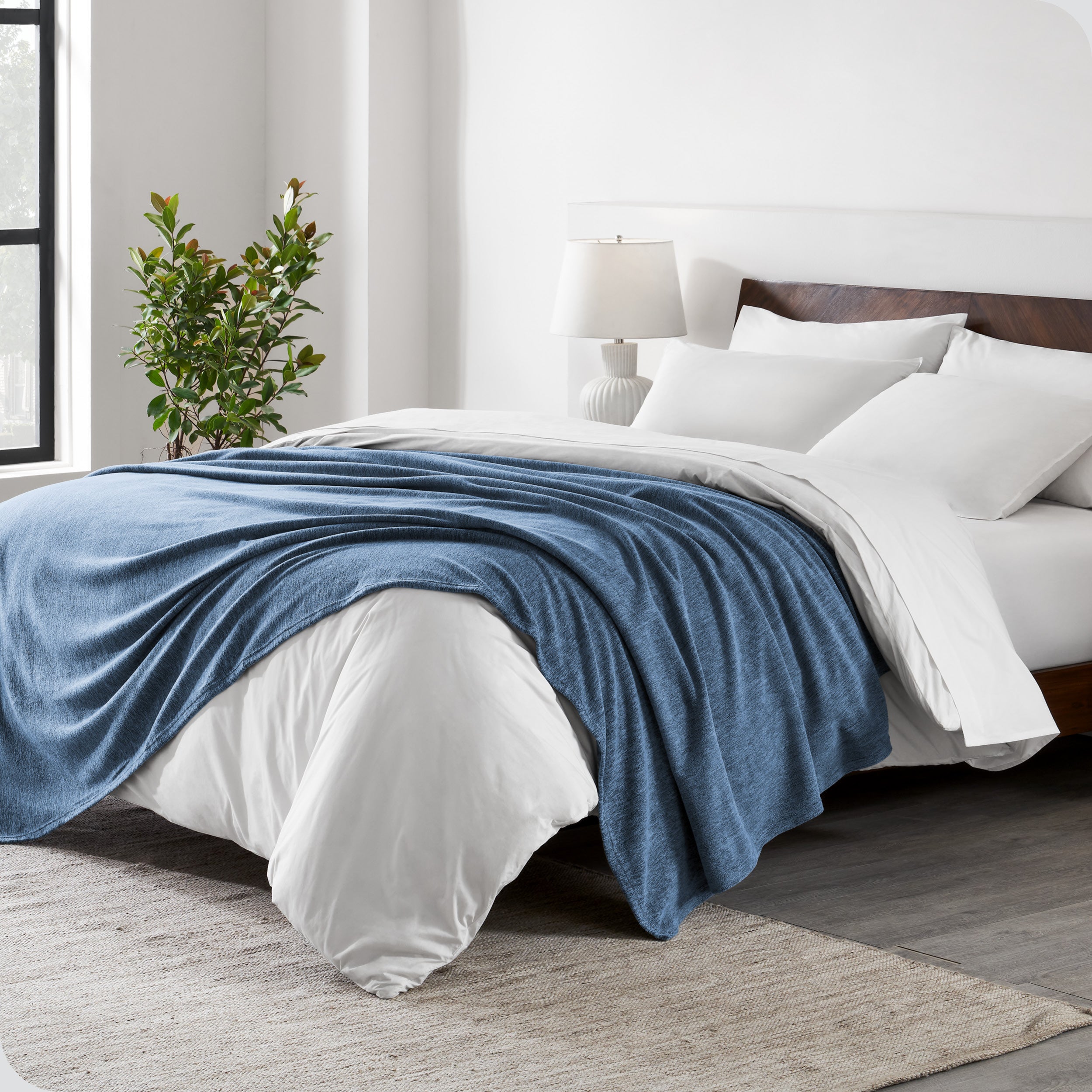 A sideview of a modern bed with a wooden bedframe and our polar fleece blanket on top of the bed.
