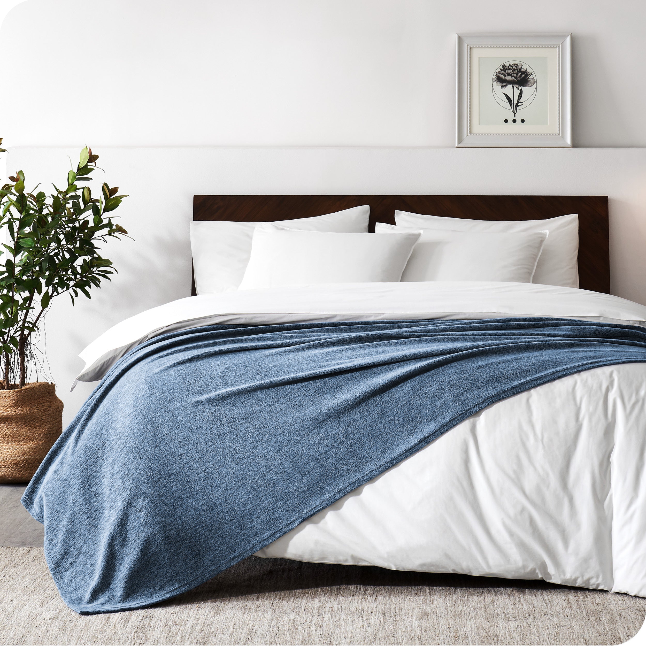 A sideview of a modern bed with a wooden bedframe and our polar fleece blanket on top of the bed.
