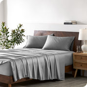 Modern bedroom with a bed against a white wall with a nightstand next to the bed. The bed has bamboo sheets draped over it.