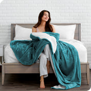 Woman cuddling with a sherpa blanket while sitting on the end of a bed