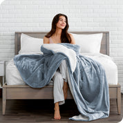 Woman cuddling with a sherpa blanket while sitting on the end of a bed