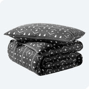 A folded stack of a printed flannel duvet cover with one pillow on top.