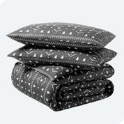 A folded stack of a printed flannel duvet cover with two pillows on top.