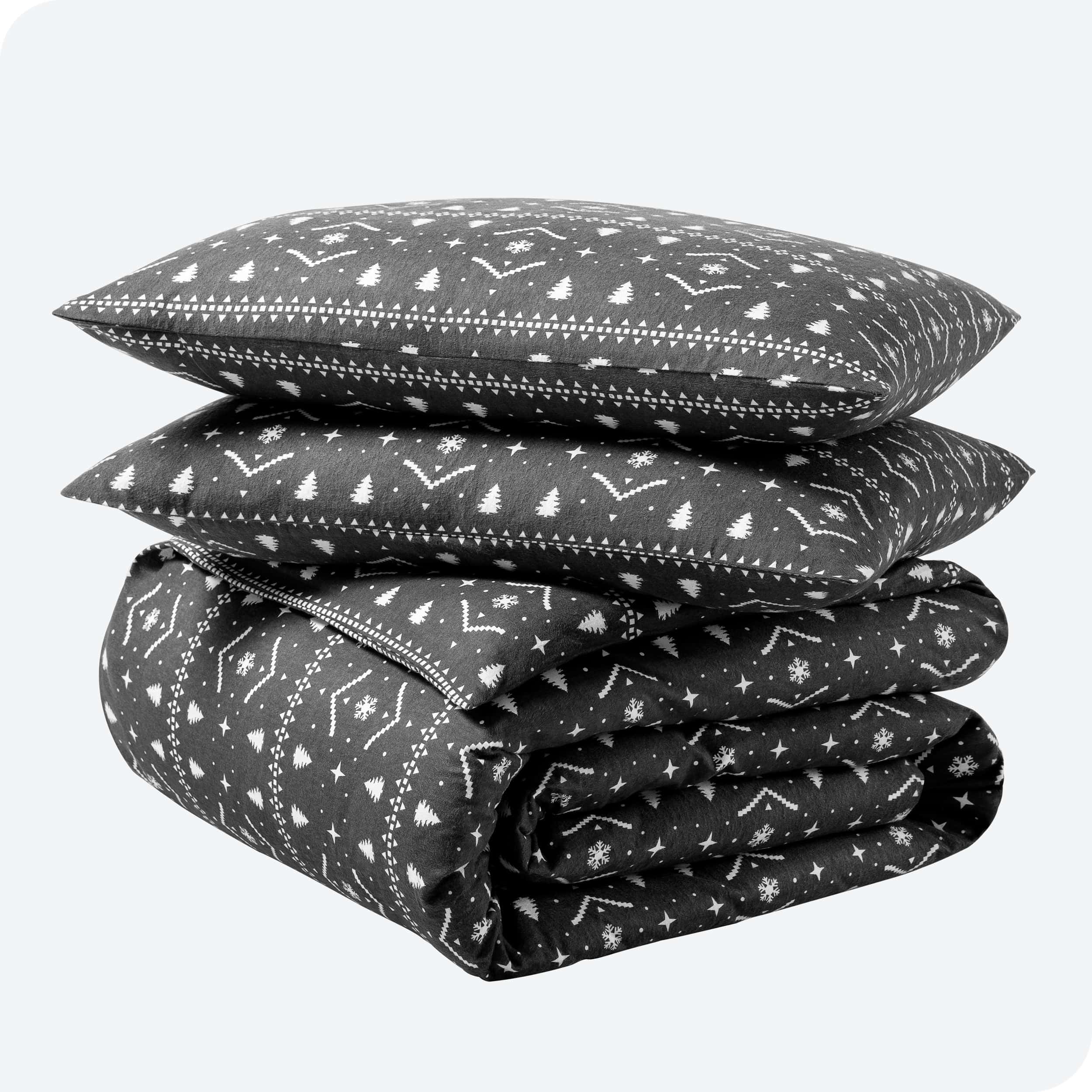 A folded stack of a printed flannel duvet cover with two pillows on top.