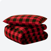 A folded stack of a printed flannel duvet cover with one pillow on top.