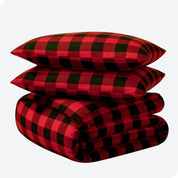 A folded stack of a printed flannel duvet cover with two pillows on top.