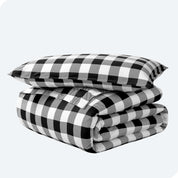 A folded stack of a printed flannel duvet cover with one pillow on top.