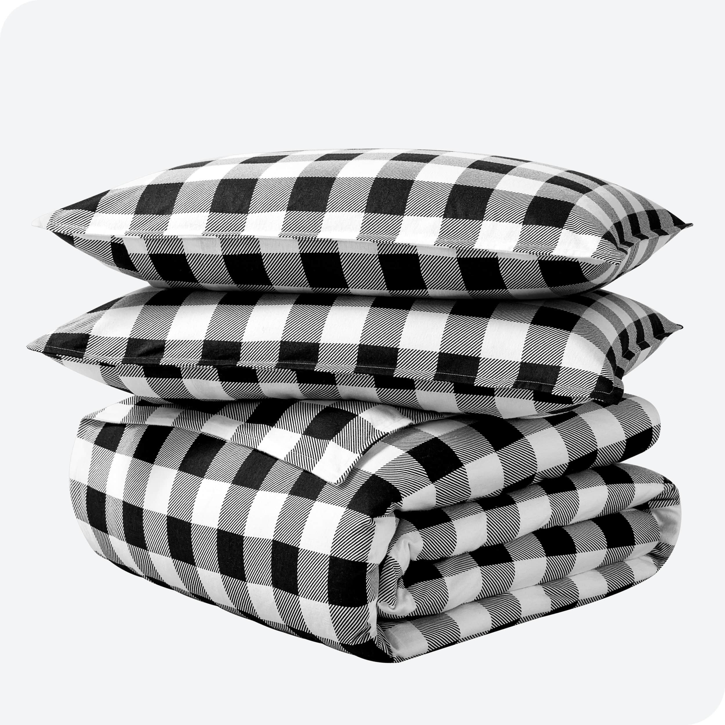 A folded stack of a printed flannel duvet cover with two pillows on top.