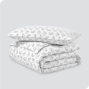 A folded stack of a printed flannel duvet cover with one pillow on top.