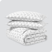 A folded stack of a printed flannel duvet cover with two pillows on top.
