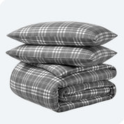 A folded stack of a printed flannel duvet cover with two pillows on top.