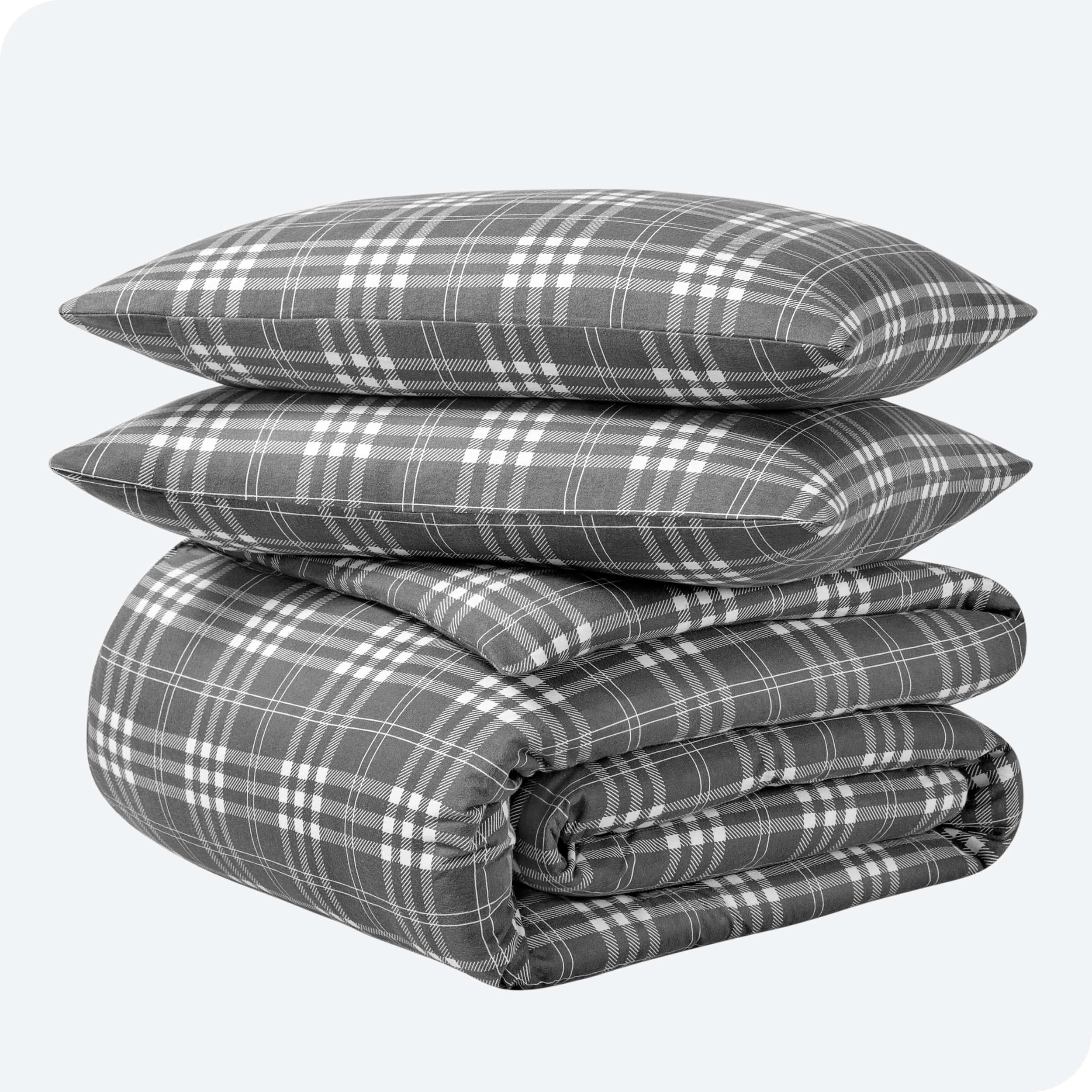 A folded stack of a printed flannel duvet cover with two pillows on top.