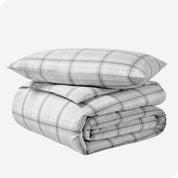 A folded stack of a printed flannel duvet cover with one pillow on top.
