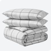 A folded stack of a printed flannel duvet cover with two pillows on top.