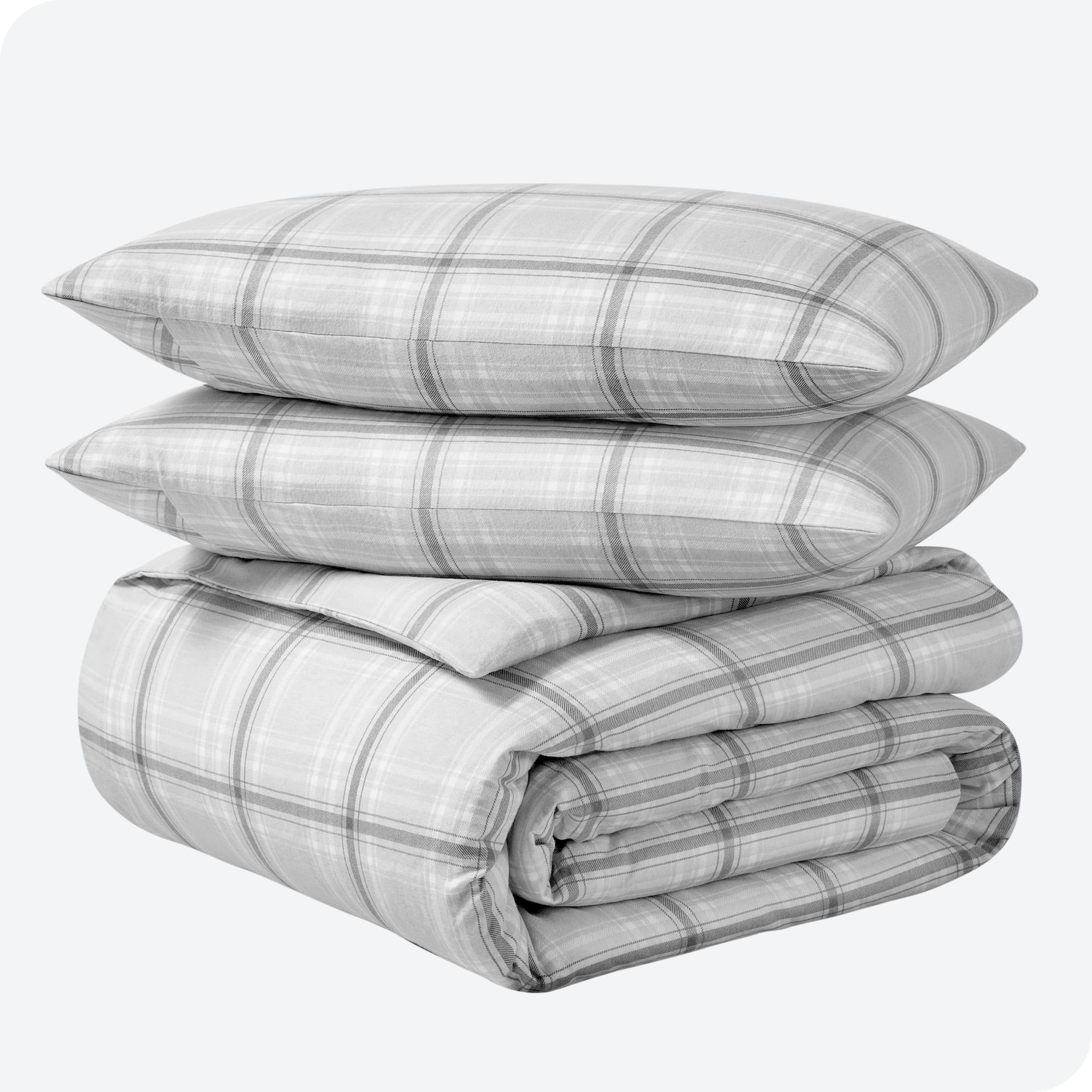 A folded stack of a printed flannel duvet cover with two pillows on top.