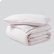 A folded stack of a printed flannel duvet cover with one pillow on top.